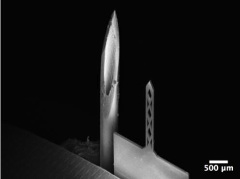 開孔鈦基微針（200um寬，50um厚，1500um長）和26G皮下注射針（外徑464um）對比的掃描電子顯微鏡照片